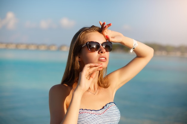 Mujer relajante tomando el sol cerca de la playa de la laguna azul en el complejo de Maldivas con protección solar