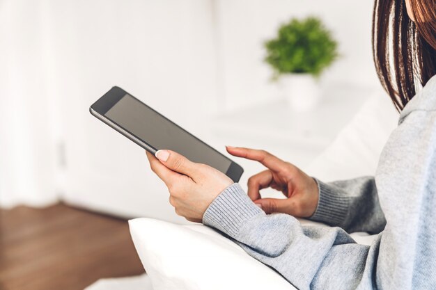 Mujer relajante y usando tableta digital en una cama
