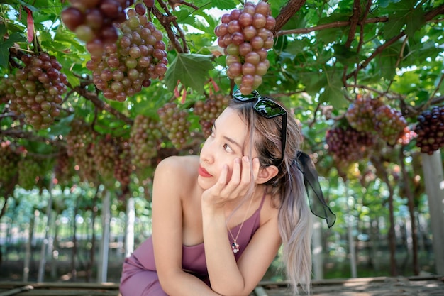 Mujer relajante con uvas naturales en viña