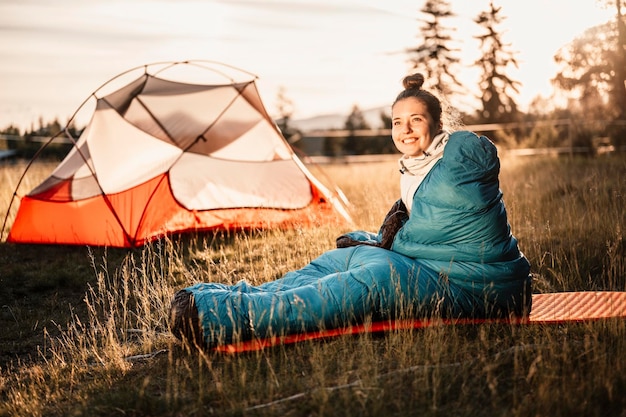 Mujer relajarse y acostarse en un saco de dormir en la tienda Atardecer acampar en el bosque Montañas paisaje viajar estilo de vida acampar Viajes de verano aventura al aire libre