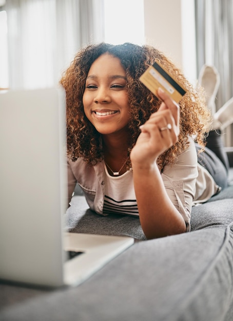 Mujer relajarse y tarjeta de crédito con portátil en el sofá para transacción de transferencia de saldo y pago de deuda Finanzas domésticas y persona con fintech para pago bancario en línea y verificación de pago
