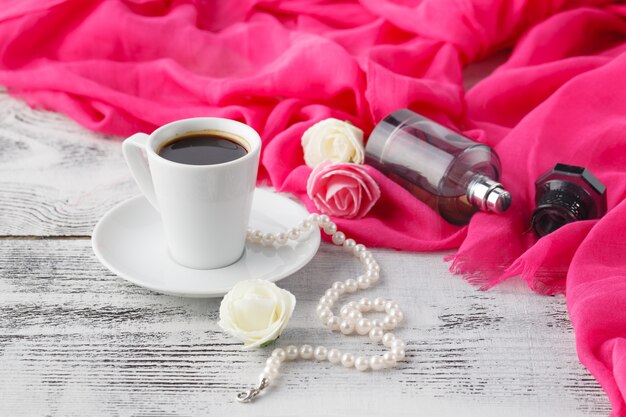 Mujer relajarse tiempo de café con chal y botella de perfume en la mesa