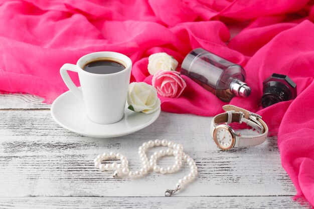 Mujer relajarse tiempo de café con chal y botella de perfume en la mesa