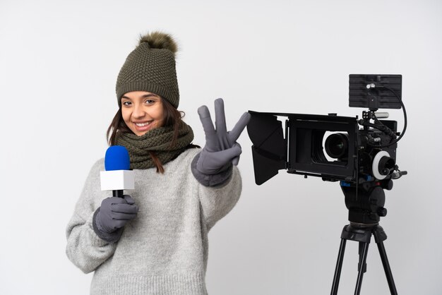 Mujer reportera sosteniendo un micrófono y reportando noticias felices y contando tres con los dedos