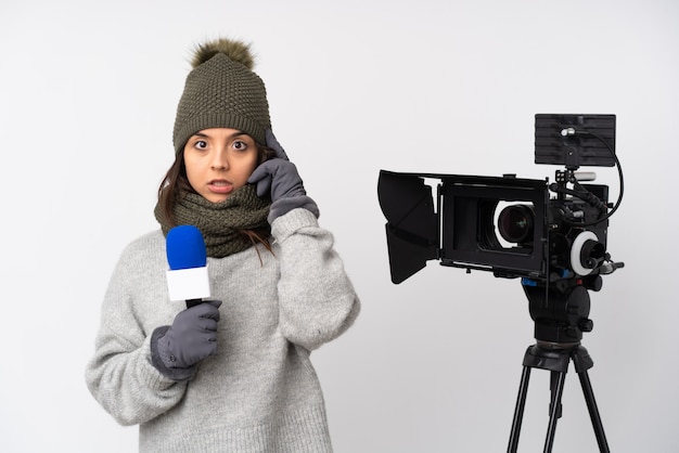 Mujer reportera sosteniendo un micrófono y reportando noticias sobre una pared blanca aislada pensando en una idea
