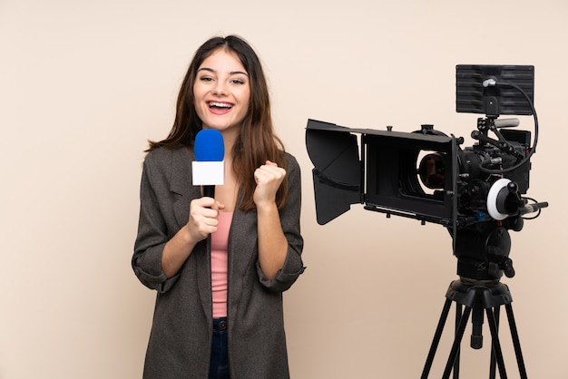 Mujer reportera sosteniendo un micrófono y reportando noticias sobre la pared celebrando una victoria