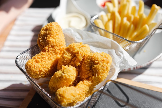 Una mujer en un restaurante o cafetería de comida rápida come alitas fritas rebozadas con diferentes salsas y papas fritas