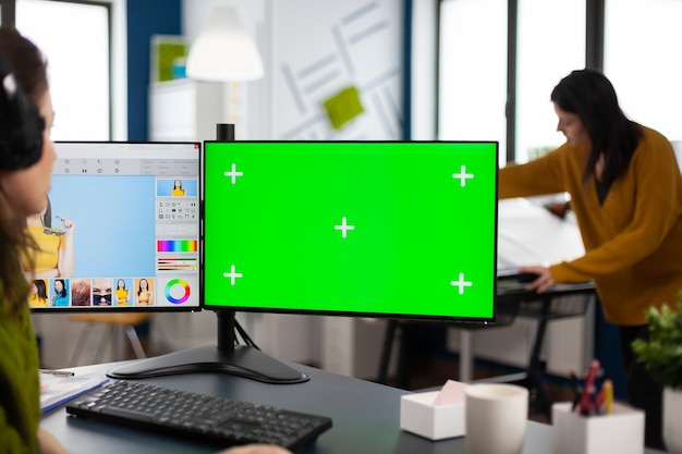 Foto mujer retocadora trabajando en un conjunto de fotos en un software de edición de fotos usando pantalla verde, pantalla aislada de clave de croma de la computadora