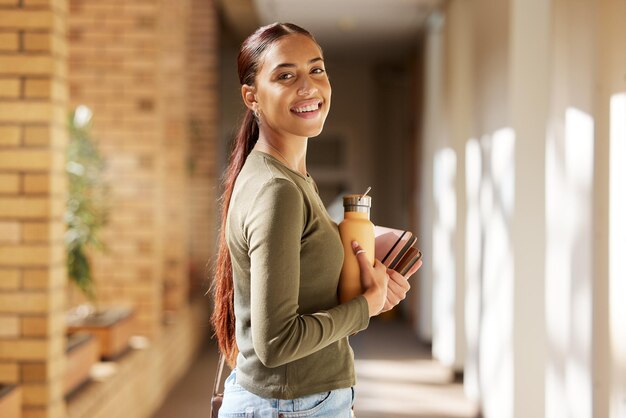 Foto mujer retrato estudiante universitario y libros universitarios y botella de agua mientras camina en el campus con una sonrisa gen z mujer feliz por la educación, el aprendizaje y el futuro después de estudiar en el edificio de la escuela