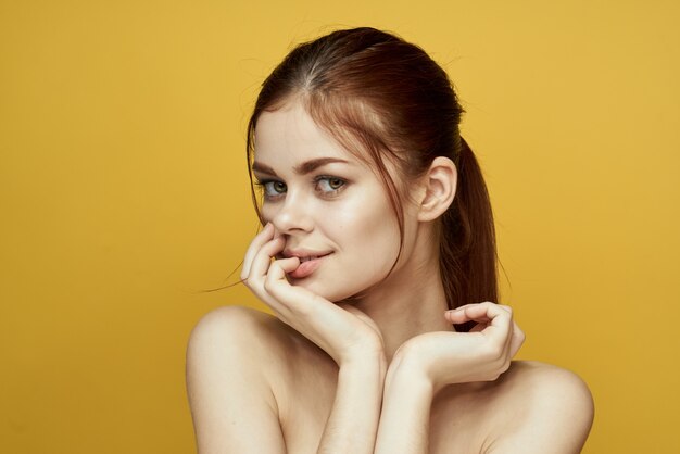 Mujer con retrato de piel hermosa con sonrisa sobre fondo amarillo