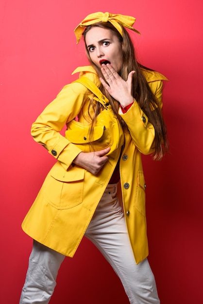 Mujer retro sorprendida en abrigo de otoño amarillo con estilo de moda de bolso de cuero