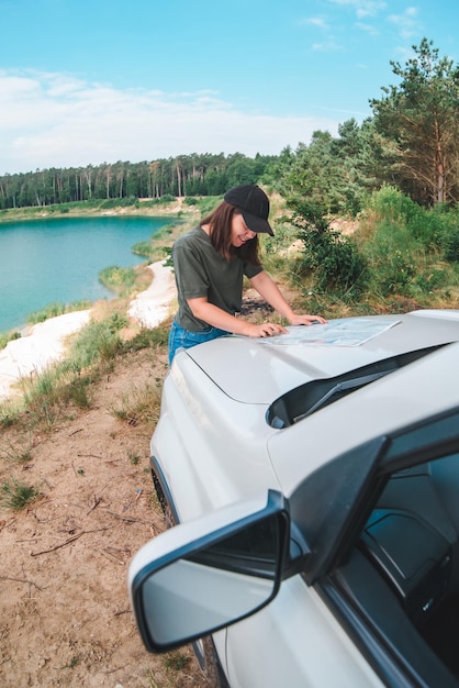 Mujer revisando con el mapa en el lago del capó del automóvil suv con agua azul en el espacio de copia de fondo