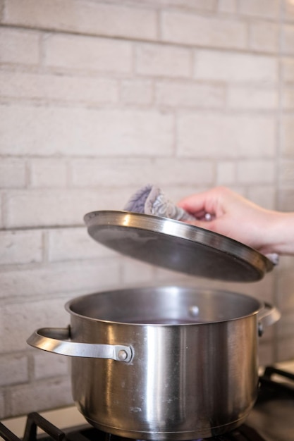 Mujer revisando la olla en la estufa agua hirviendo