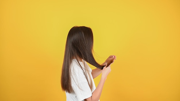 Mujer revisando la punta de su cabello en busca de puntas abiertas Concepto de cuidado del cabello Foto de alta calidad