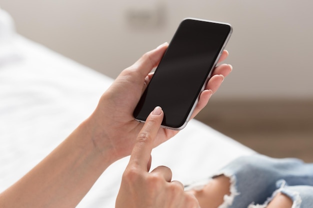 Mujer revisando el teléfono celular en la cama