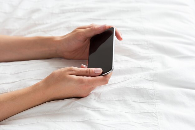 Mujer revisando el teléfono celular en la cama