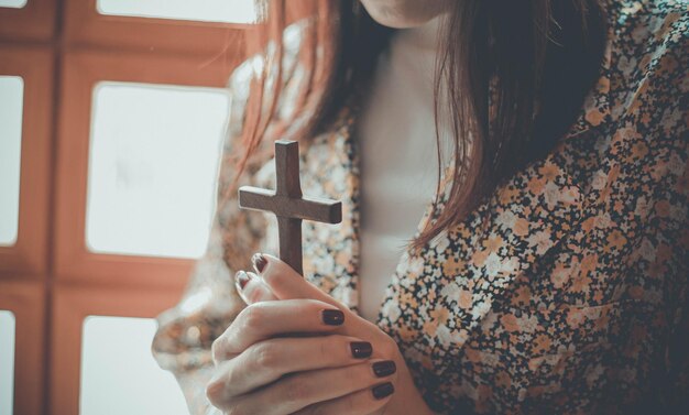 Una mujer reza y sostiene una cruz.