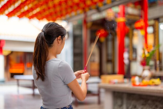 Mujer rezando con incienso en un templo chino