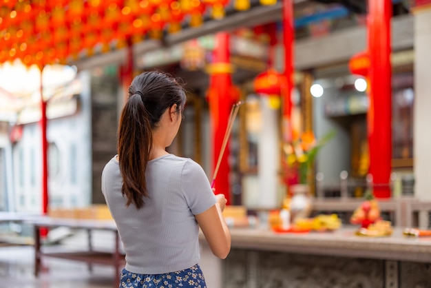 Mujer rezando con incienso en un templo chino