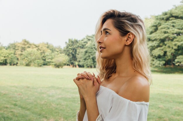 Mujer rezando por la mañana en el parque. Concepto de amor de esperanza de fe de cristianismo.