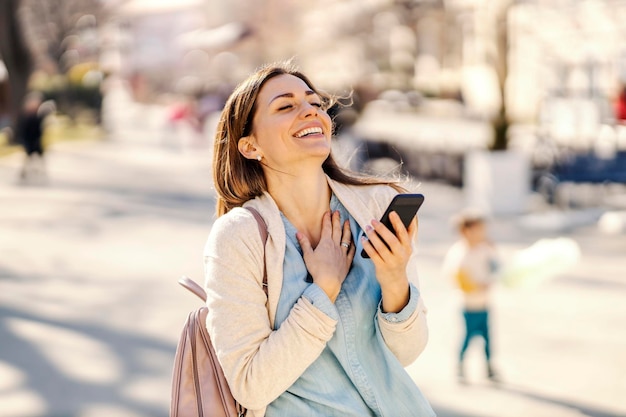 Una mujer se ríe mientras lee un mensaje por teléfono en un parque