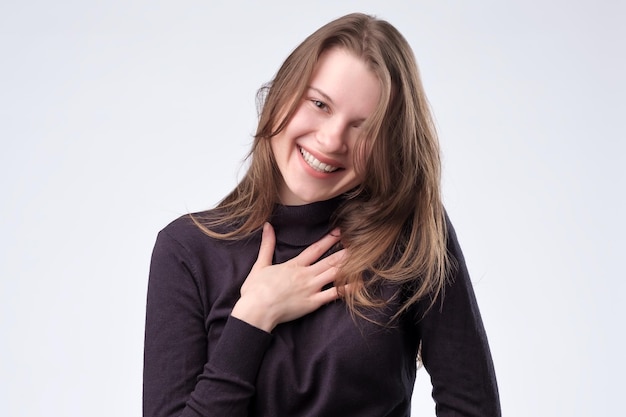 Mujer riendo con cabello largo sobre pared blanca