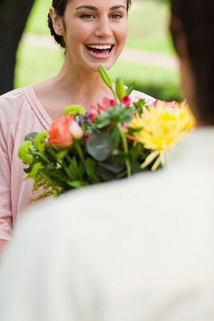 Foto mujer riendo mientras se presenta con flores