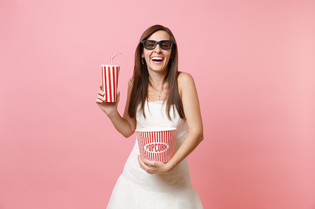 Mujer riendo con vestido blanco gafas 3d viendo una película con un cubo de palomitas de maíz, un vaso de plástico de refresco o cola