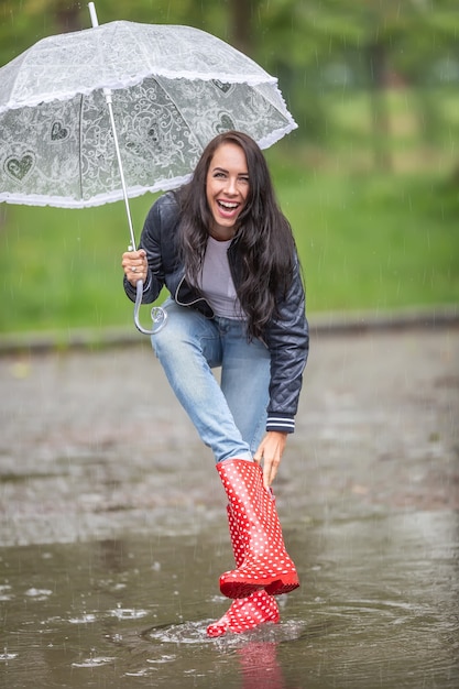 Mujer riéndose de agua goteando a su bota de lluvia