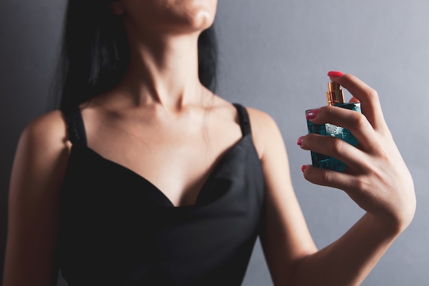 Mujer rocía perfume en su cuello