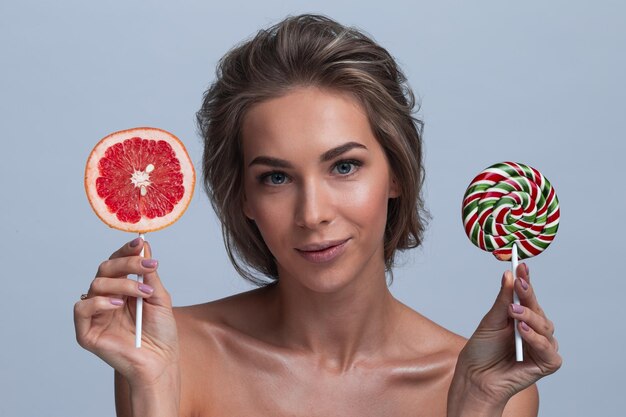 Mujer con rodaja de pomelo y piruleta