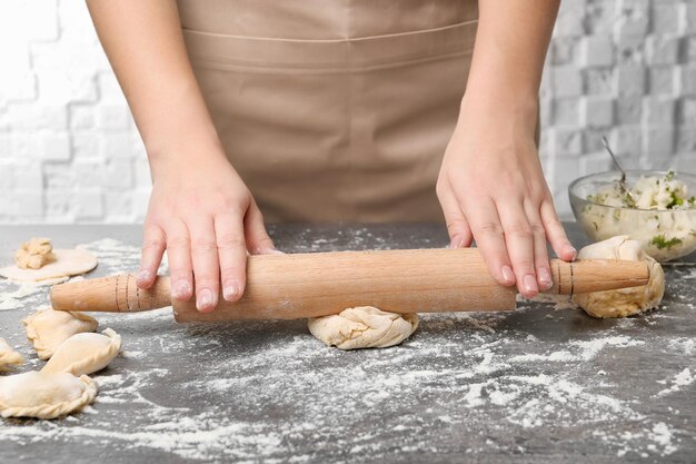 Mujer rodando la masa en el primer plano de la mesa