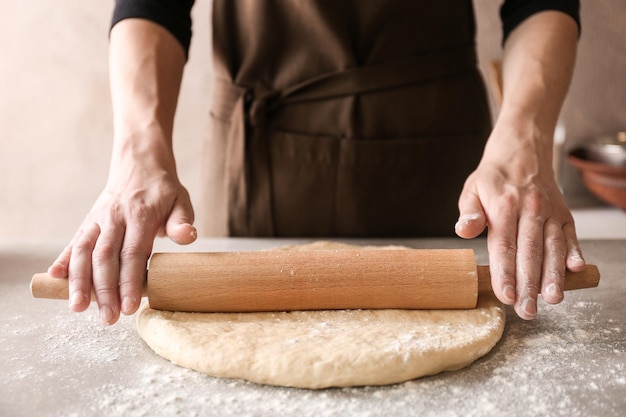 Mujer rodando masa para rollos de canela en la mesa de la cocina