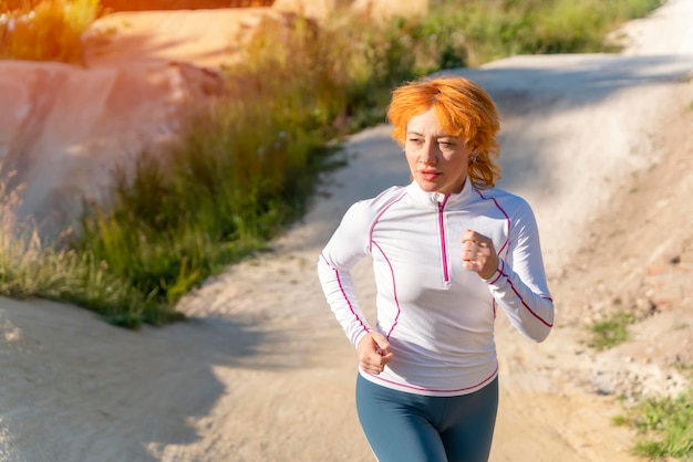 Mujer roja corriendo afuera contra el cielo azul