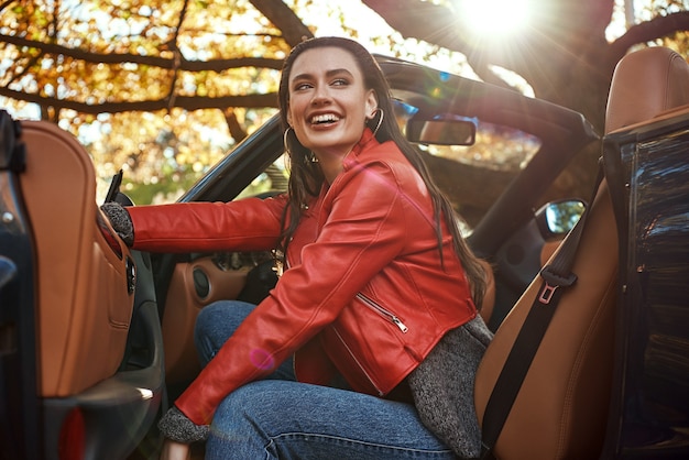 Mujer de rojo en cabriolet ella está sonriendo