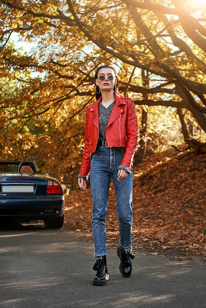 Mujer en rojo cerca de cabriolet con gafas de sol