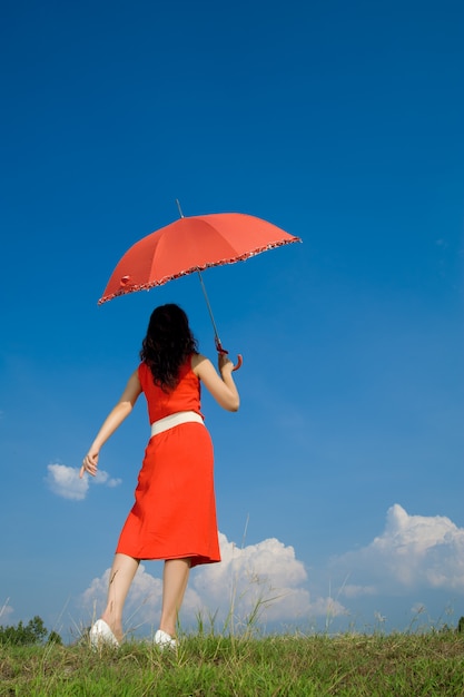 Mujer en rojo con paraguas y cielo azul