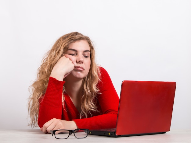 mujer en rojo, trabajando remotamente en la computadora en blanco.