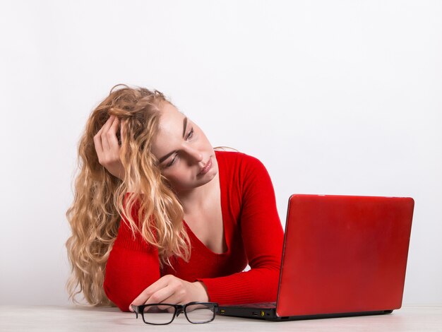 mujer en rojo, trabajando remotamente en la computadora en blanco.