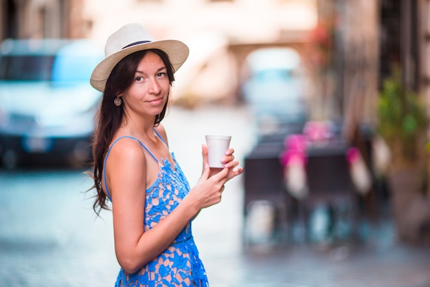 Mujer en Roma con café para ir de viaje de vacaciones. Muchacha caucásica feliz sonriente que se divierte que ríe en el café italiano de la acera durante vacaciones en Roma, Italia, Europa.