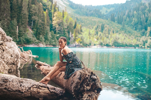 Mujer romántica feliz sentada junto al lago salpicando agua