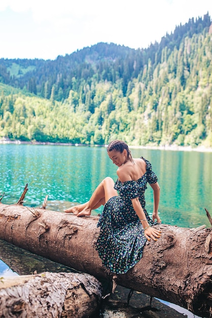 Mujer romántica feliz sentada junto al lago salpicando agua