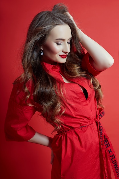 Mujer romántica con largo cabello rubio en vestido rojo.