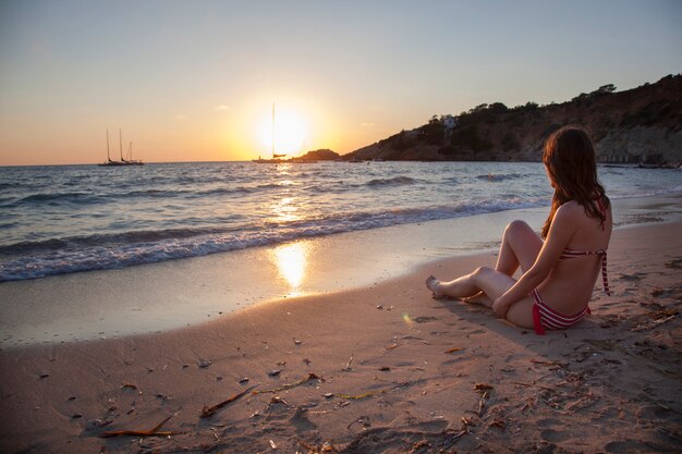 Mujer romántica en una puesta de sol en Ibiza mirando el mar