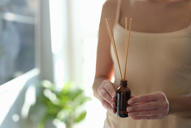 Mujer romántica sosteniendo un difusor con palos de bambú.