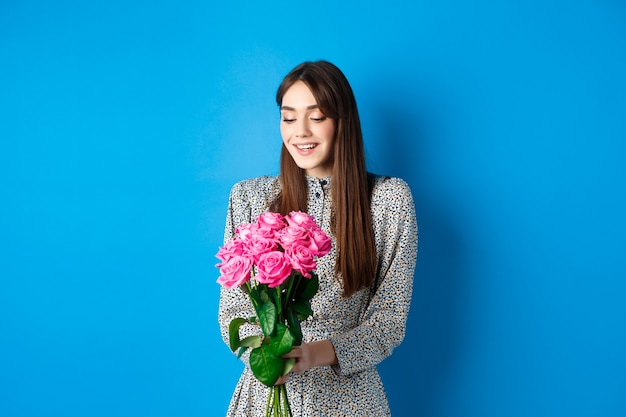 Mujer romántica en vestido mirando feliz a las flores