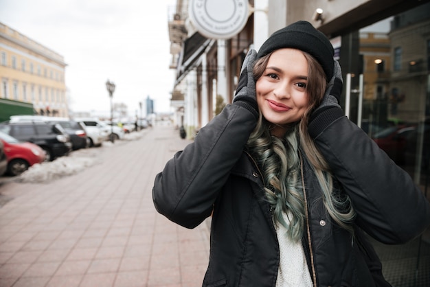 Mujer en ropa de abrigo escuchando música en la calle