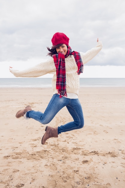 Mujer en ropa de abrigo con estilo saltando en la playa
