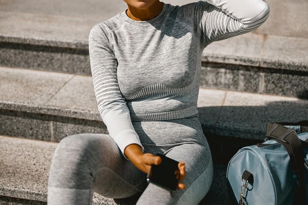 Mujer con ropa activa gris claro descansando después de hacer ejercicio al aire libre