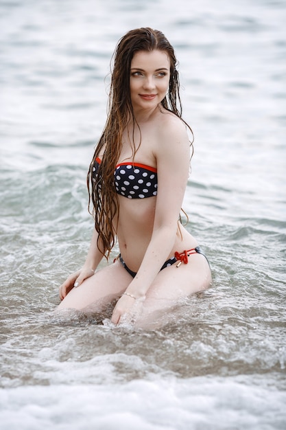 Mujer en ropa blanca refrescante a la orilla del mar.